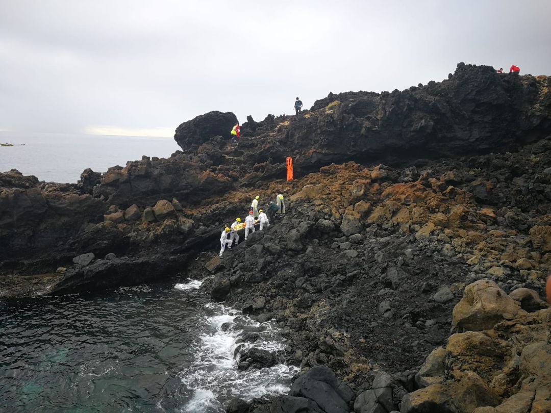 Los servicios de emergencias rescatando a uno de los migrantes en el Charco del Palo.