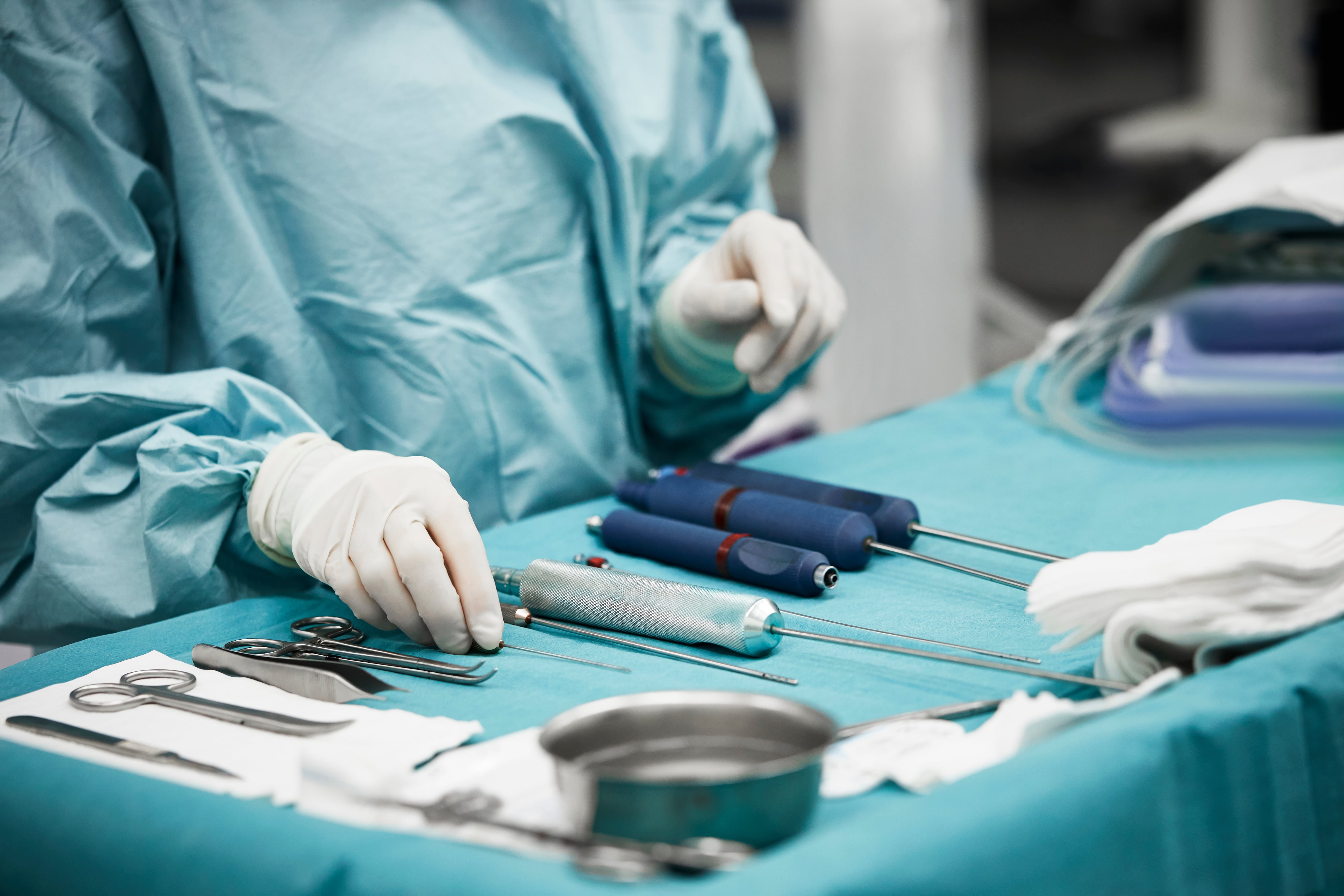 Midsection of female plastic surgeon arranging surgical equipment on table. Young doctor is preparing for operation. She is in emergency room at hospital.