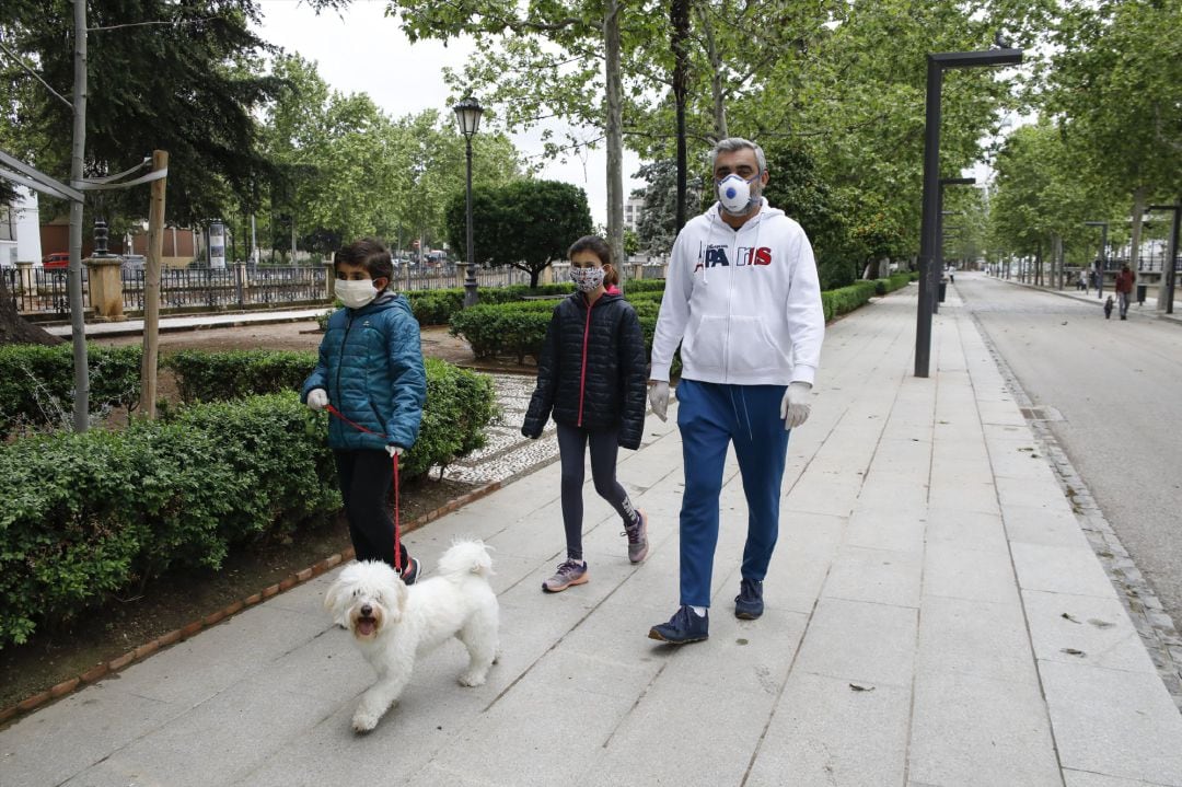 Dos niños con mascarillas acompañados por su padre pasean al perro ,en Granada.