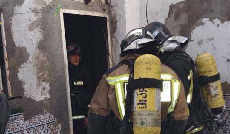 Miembros del cuerpo de Bomberos actúan en la vivienda incendiada en la calle Corta del Cerro del Águila