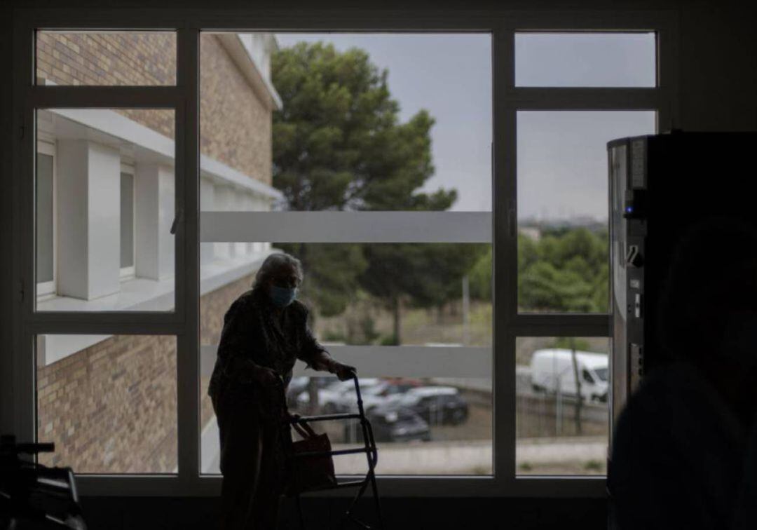 Una anciana pasea con mascarilla y andador por su residencia, en una imagen de archivo