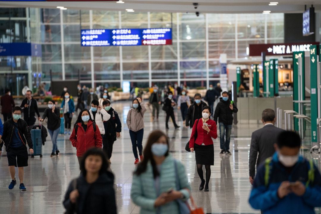 Los viajeros y los miembros de la tripulación de la aerolínea usan máscaras quirúrgicas como medida de protección contra el mortal coronavirus en el aeropuerto internacional de Hong Kong