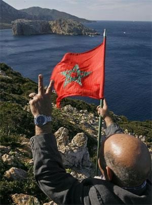 Activistas del Comité de Liberación de Ceuta y Melilla se fotografían portando la bandera marroquí con el islote de Perejil al fondo