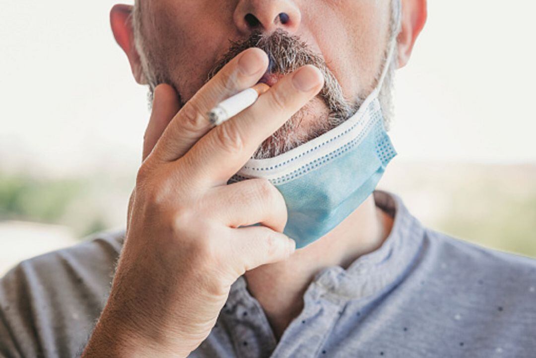 Hombre fumando con mascarilla