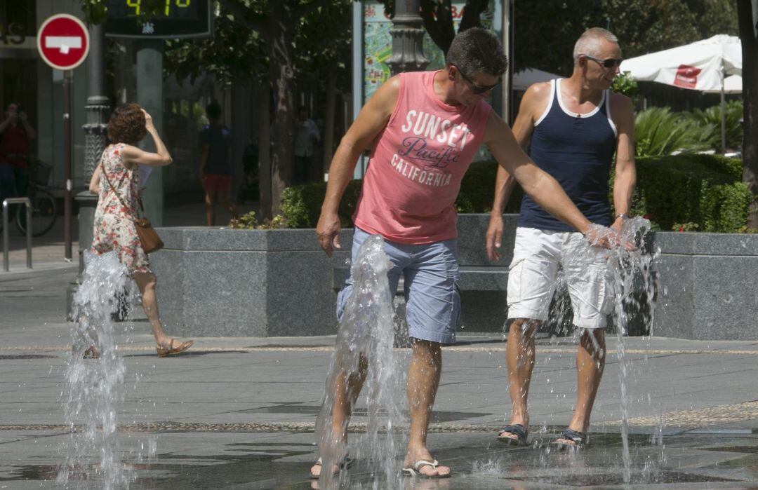 Dos hombres se mojan en una fuente para refrescarse ante las altas temperaturas.