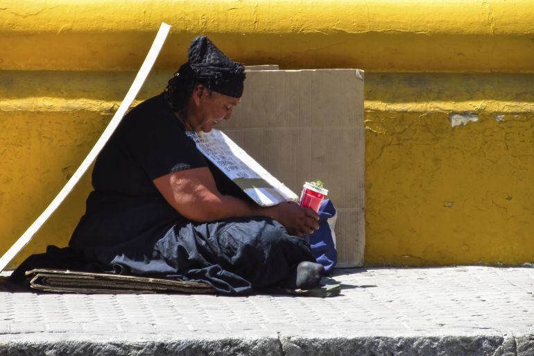 Una mujer pide en la calle. 