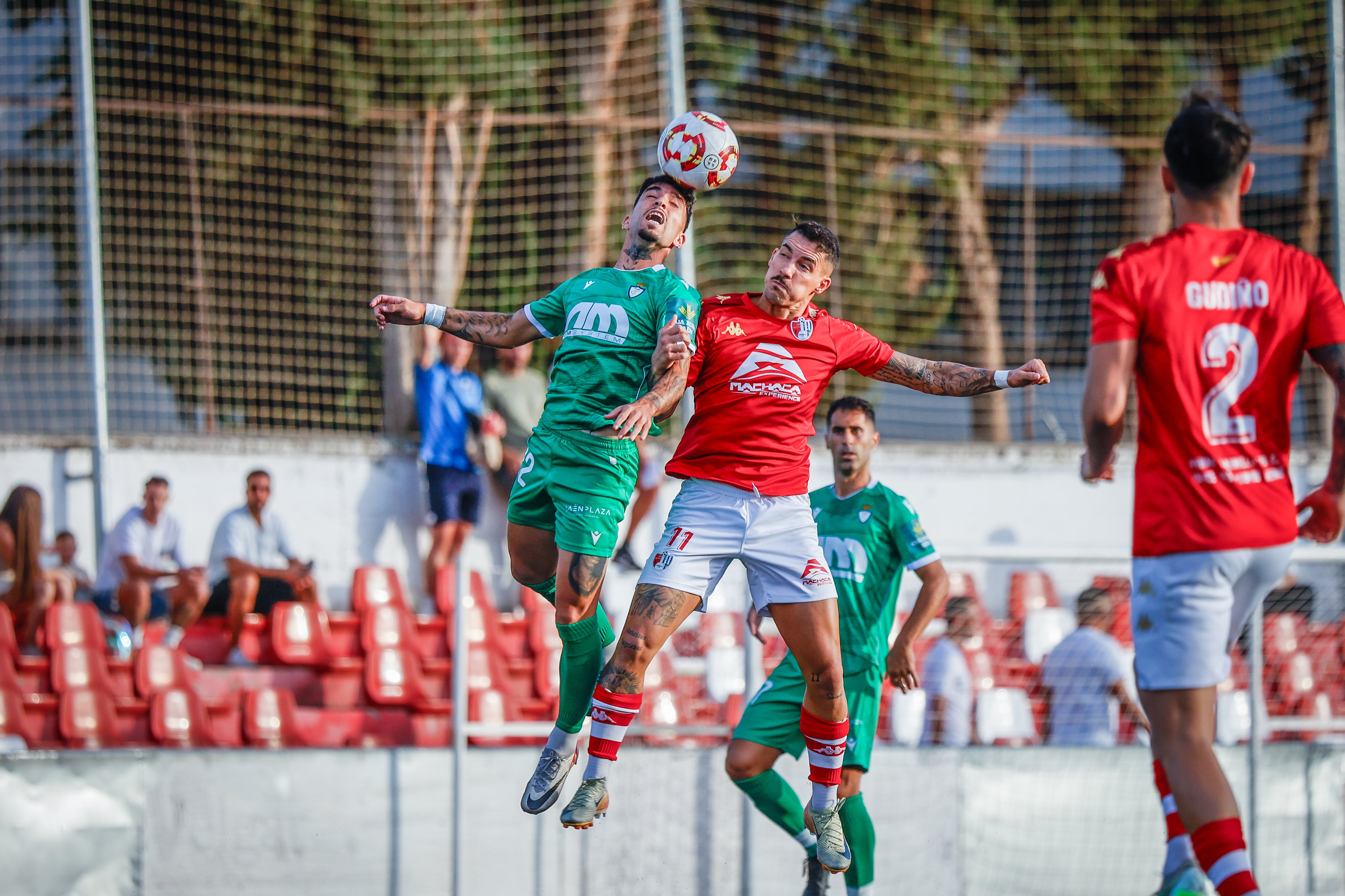 Óscar Lozano salta con Israel en la pugna por un balón en el encuentro Arenas de Armilla - Real Jaén.