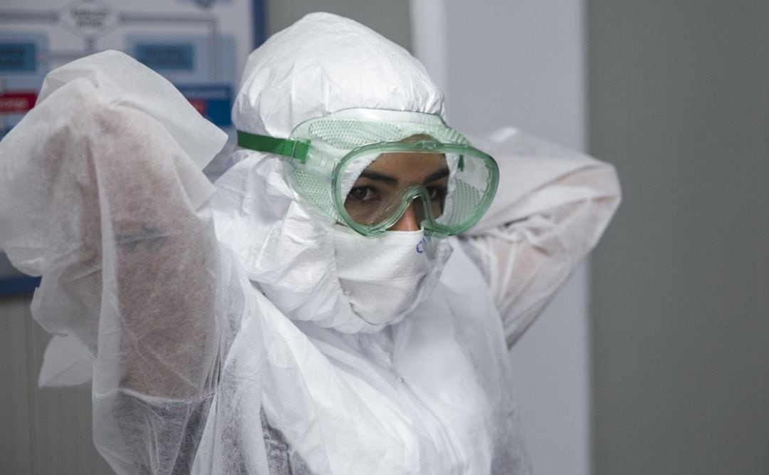 Una profesional sanitaria se coloca un Equipo de Protección Individual.
