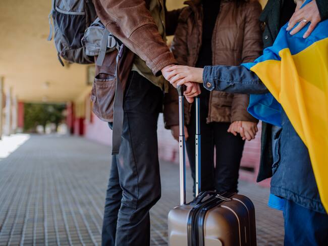Ukrainian refugee family waiting for train in station, Ukrainian war concept.