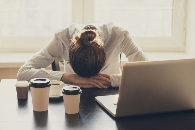 Una joven, rodeada de cafés, ante su ordenador