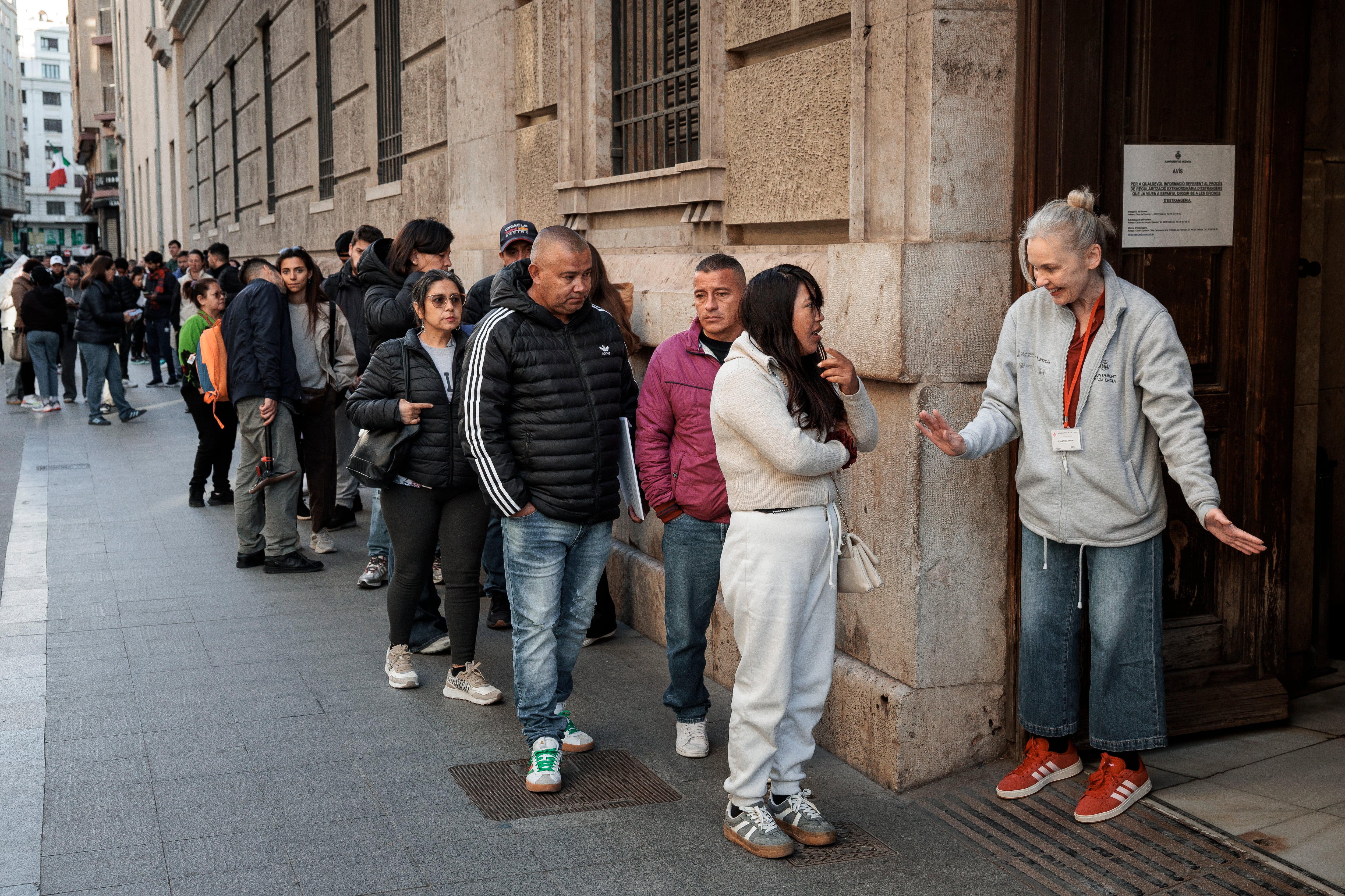Personas haciendo cola en una oficina para solicitar la regularización.