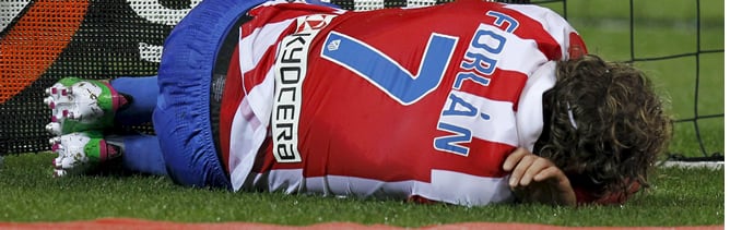 El delantero uruguayo del Atlético de Madrid, Diego Forlán, cae lesionado sobre el terreno de juego durante el partido, correspondiente a la ida de los octavos de final de la Copa del Rey, que el conjunto rojiblanco disputa contra el RCD Espanyol esta noc