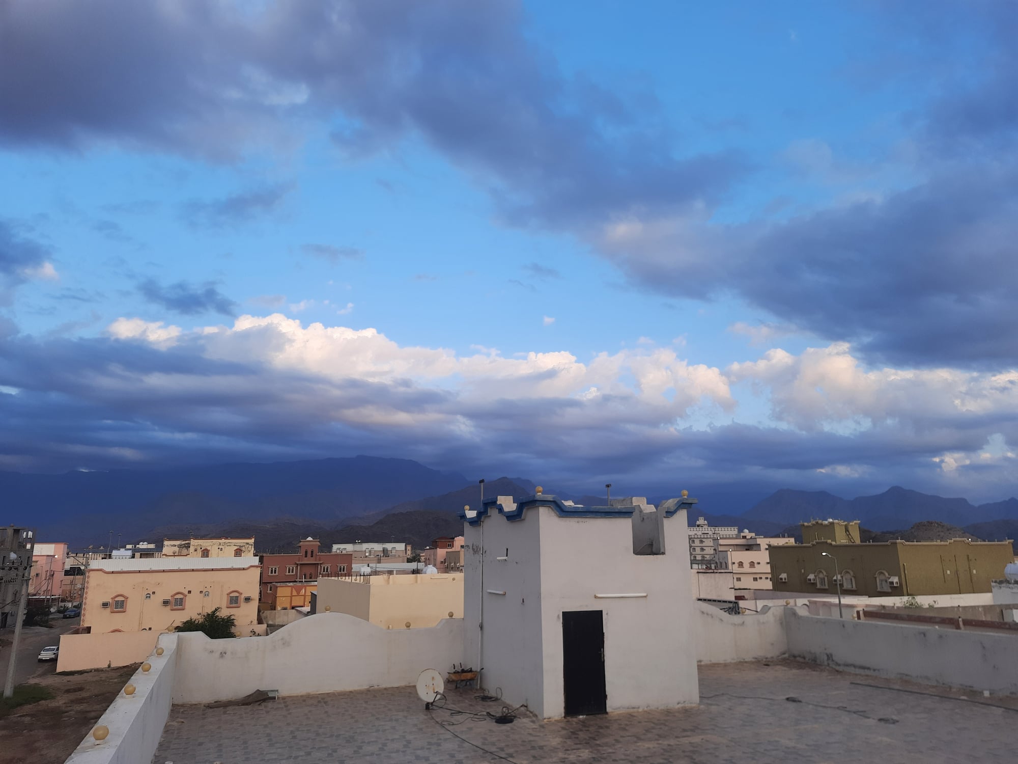 A bird&#039;s eye view of the streets and buildings of a small town on a winter day under a sky full of white and gray clouds before sunset