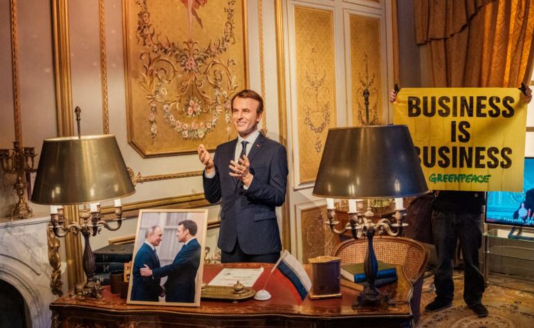 Activistas de Greenpeace despliegan una pancarta con su logo, colocan una fotografía de Macron con Putin y una bandera de Rusia, antes de robar la figura, el 2 de junio de 2025. Greenpeace.