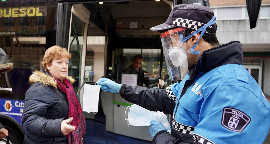 Un policía local entrega una mascarilla a una usuaria de AUVASA