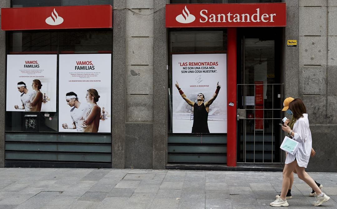 Dos mujeres pasean frente a una oficina del Banco Santander.