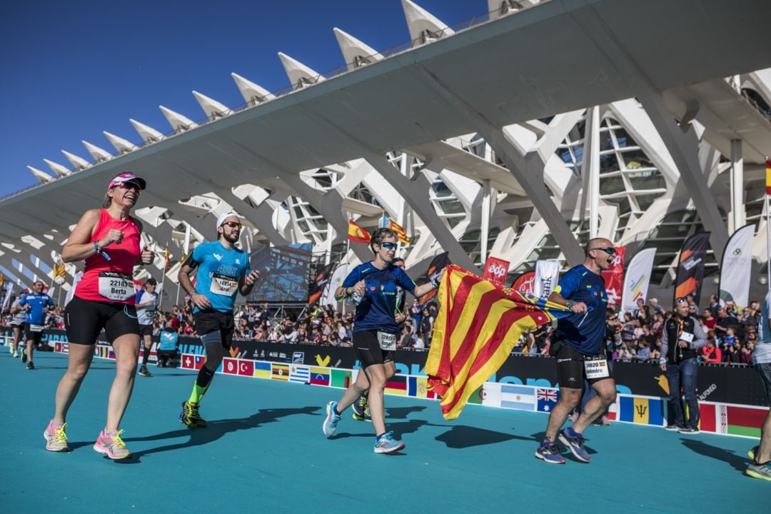 Cuatro corredores en el Maratón Valencia 2019 a su llegada a la meta, con una senyera de la Comunitat Valenciana. 