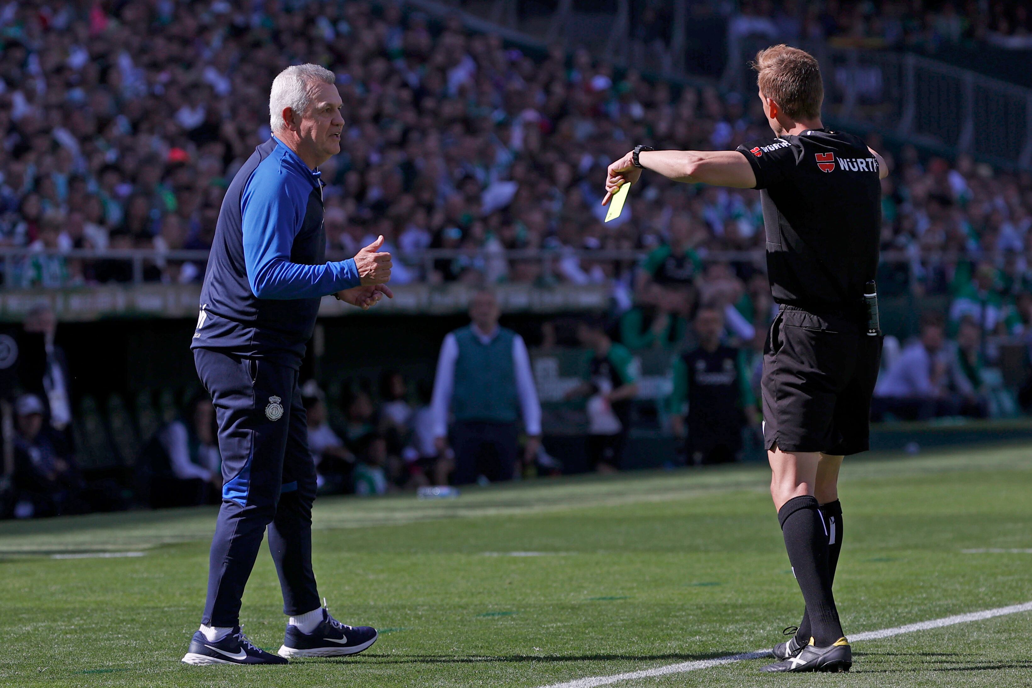 SEVILLA, 19/03/2023.- Javier Aguirre (i), entrenador del Mallorca, discute con el árbitro Pizarro Gómez tras ver la tarjeta amarilla durante el partido ante el Real Betis de la jornada 26 de LaLiga que estos dos equipos juegan hoy domingo en el estadio Benito VillamarínEFE/Julio Muñoz
