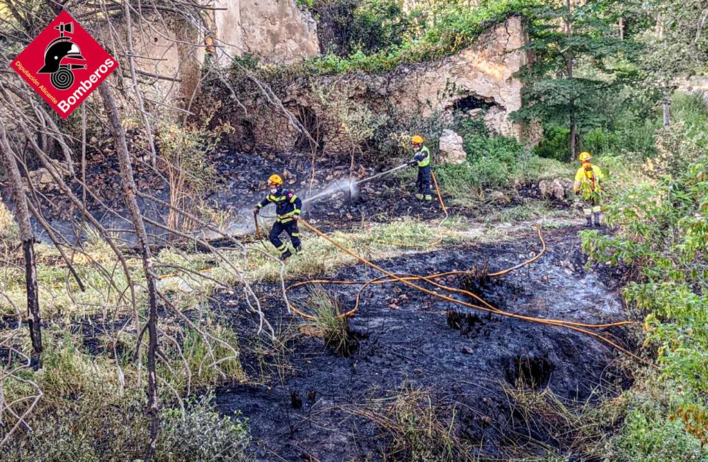 Los bomberos y bomberos forestales apagando el fuego originado cerca del río Verd en Castalla.