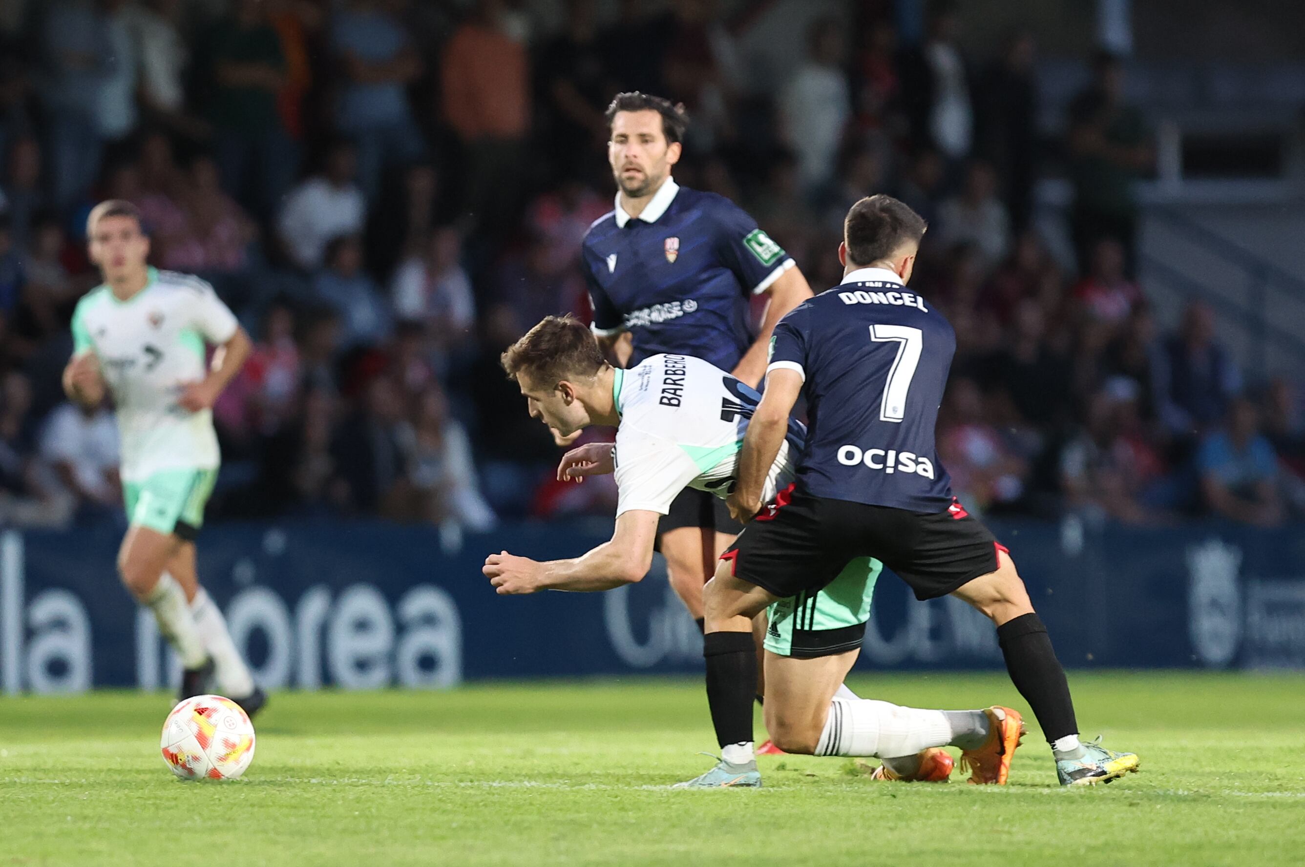 Carlos Doncel intenta frenar el avance de Barbero ante la mirada de David Fernández / Osasuna Promesas