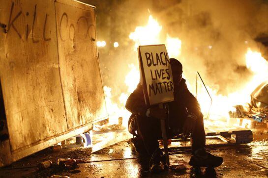 Uno de los manifestantes junto a los destrozos ocasionados por las protestas.