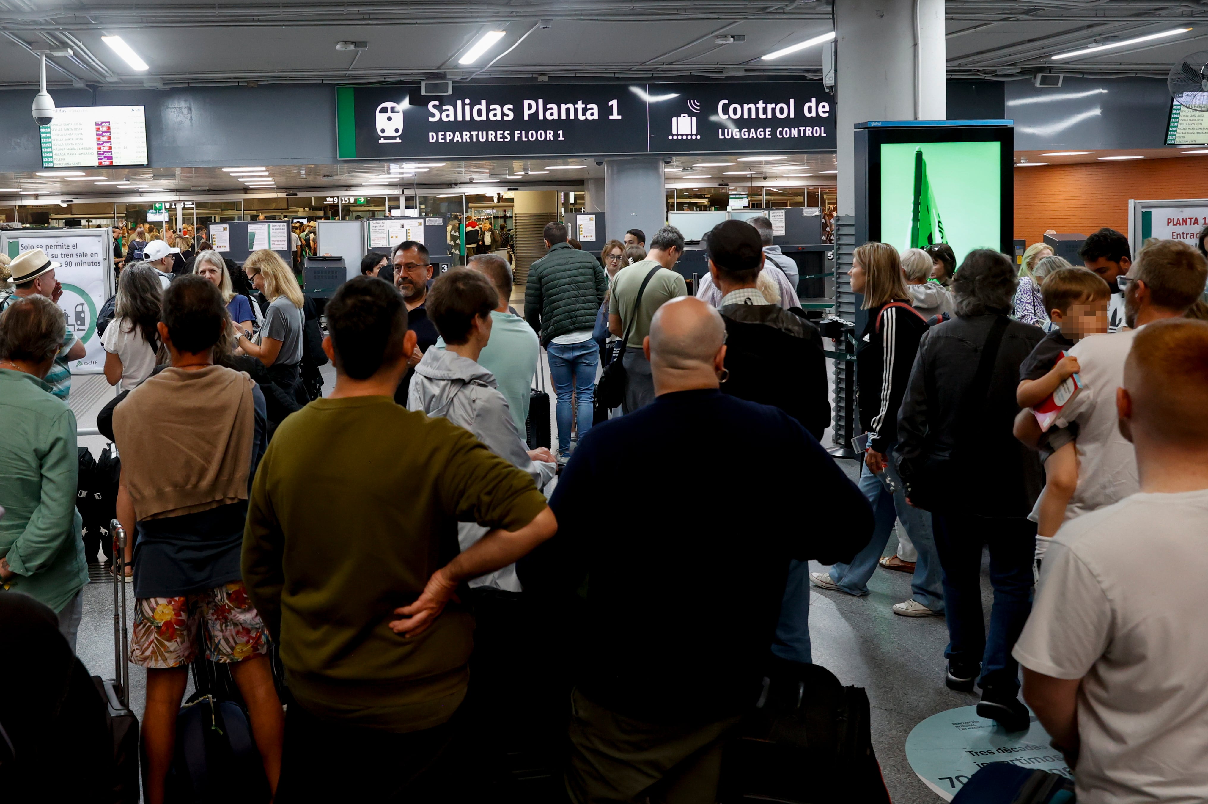 Cientos de personas esperan en la estación de tren de Atocha de Madrid donde este lunes se registran retrasos y cancelaciones de los trenes a causa de las fuertes lluvia caídas en la región.