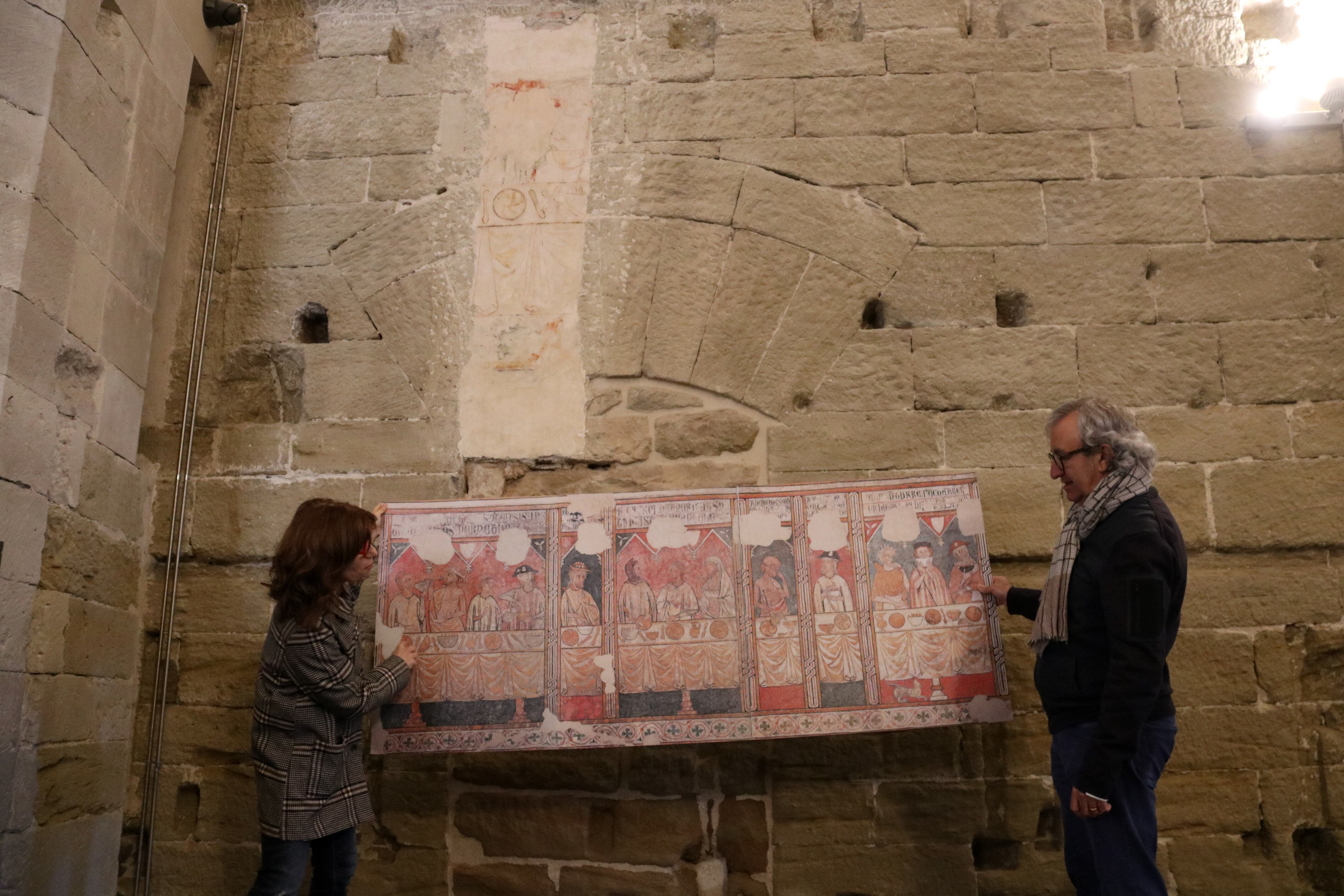 La directora del Museu de Lleida i el director del Consorci del Turó de la Seu Vella ensenyen l'indret de la Seu Vella on s'ubicava la pintura de la Pia Almoina, que ara es pot veure al Museu. Foto: ACN