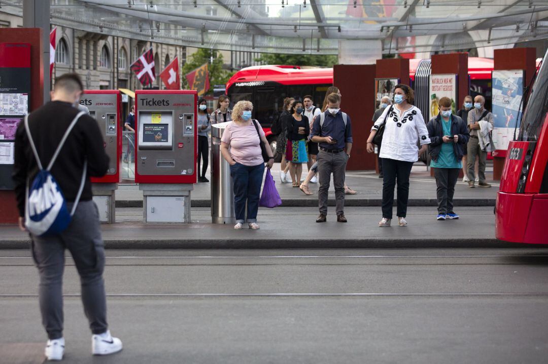Passengers wearing protective masks wait for a tram in Bern, Switzerland,