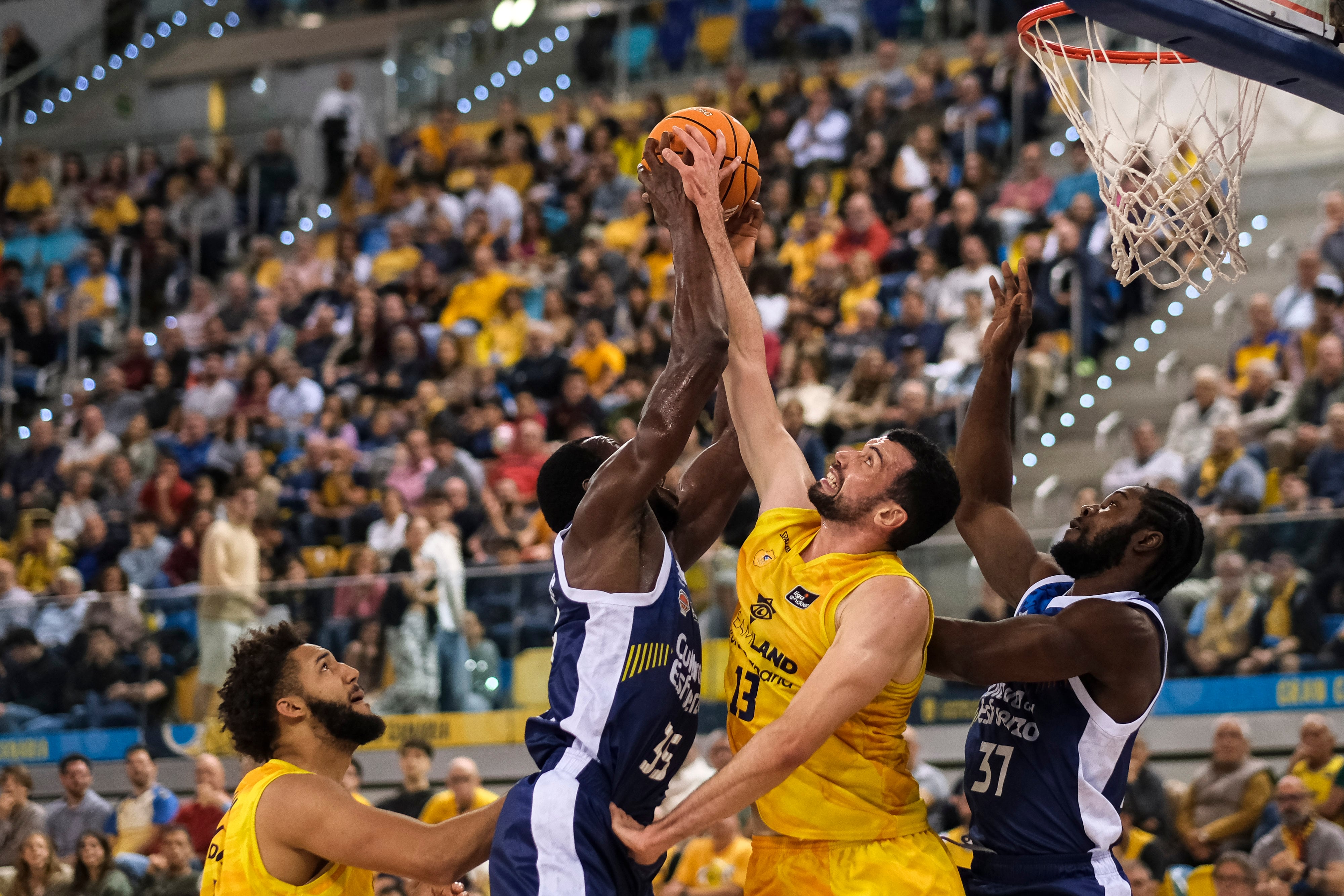 LAS PALMAS DE GRAN CANARIA, 27/12/2024.- El jugador del Valencia Basket Amida Brimah (2-i) entra a canasta ante George Conitt IV (i) y Pierre Pelos (2-d), ambos del Dreamland Gran Canaria, durante el partido de la Liga Endesa de baloncestio que ambos equipos disputan este viernes en el Gran Canaria Arena. EFE/Ángel Medina
