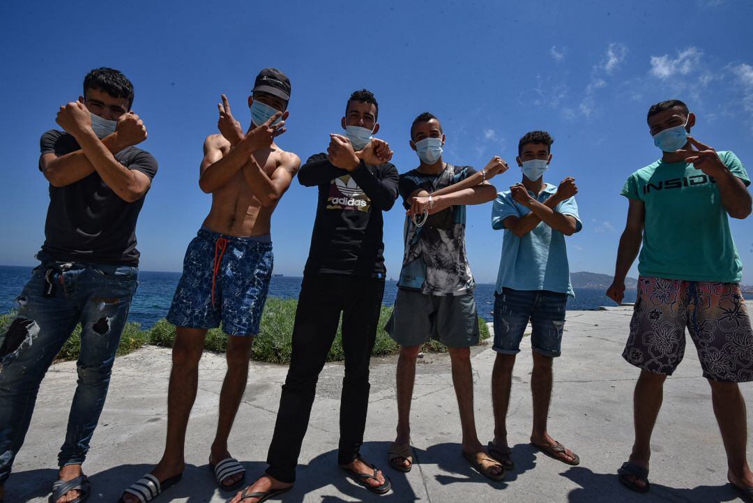 Un grupo de los migrantes que entraron a Ceuta hace 3 semanas, posan mientras esperan para recoger una bolsa de alimentos de Cáritas