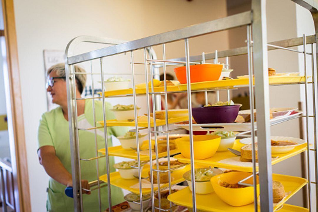 Una trabajadora recogiendo las bandejas de comida en una residencia de mayores