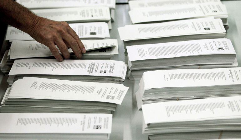 Un ciudadano coge una papeleta de una cabina en un colegio electoral del centro de Barcelona, durante los comicios municipales que se celebran hoy