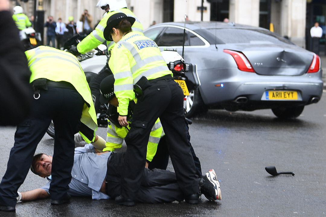 Un grupo de policías arrestan al manifestante que se ha colocado delante del coche de Boris Johnson y ha causado un accidente de tráfico 