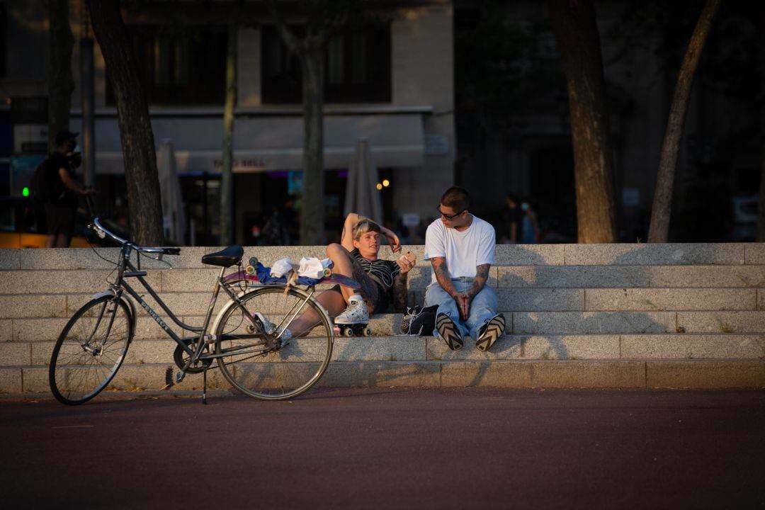 Dos jóvenes descansan junto a una bicicleta