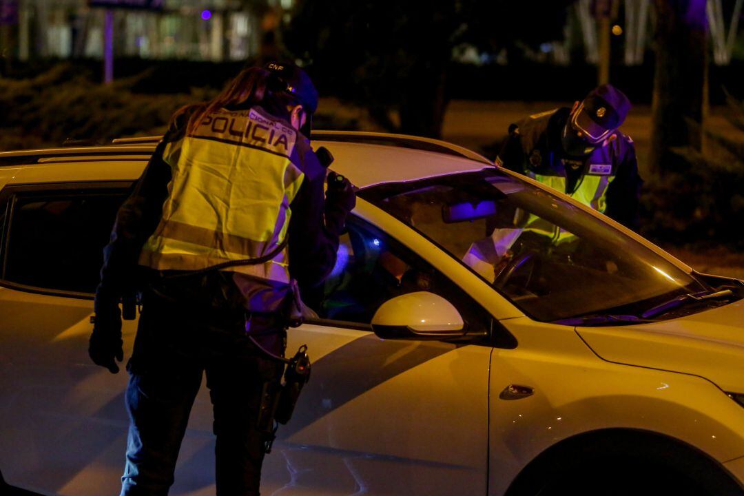 Un policía nacional para a un coche en un control policial.