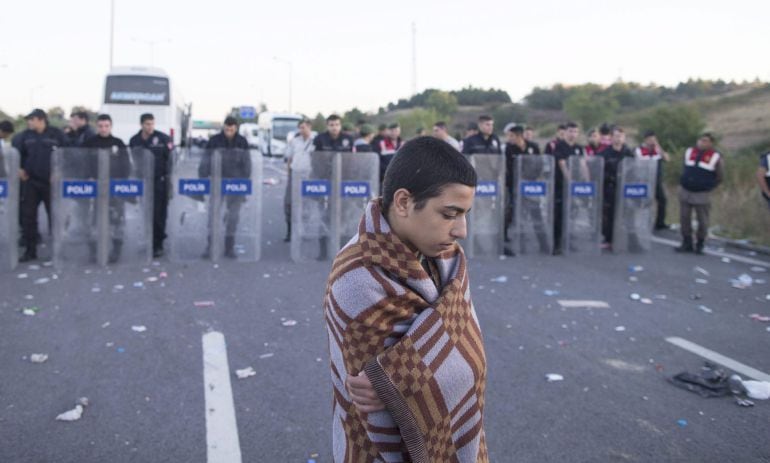 TOL01. Edirne (Turkey), 19/09/2015.- A Syrian refugee boy stands in front of riot police at the Istanbul-Edirne highway as they wait for permission to cross the Turkish Greek border to reach Germany, in Edirne, Turkey, early 19 September 2015. Turkey has spent 7.6 billion US dollar on caring for 2.2 million Syrian refugees since the civil war began in 2011, Deputy Prime Minister Numan Kurtulmus said on 18 September. Turkey hosts more Syrians who fled their homeland than any other country. Most Syrians, however, have no legal right to work and rights groups report housing remains a huge issue for many. (Siria, Alemania, Turquía) EFE/EPA/TOLGA BOZOGLU