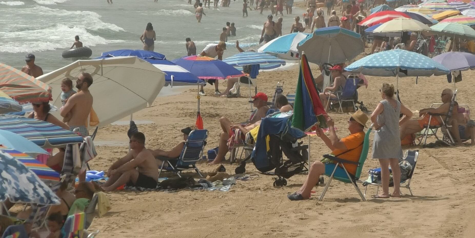 Veraneantes se refugian del calor en la playa de Arenales del Sol de Elche