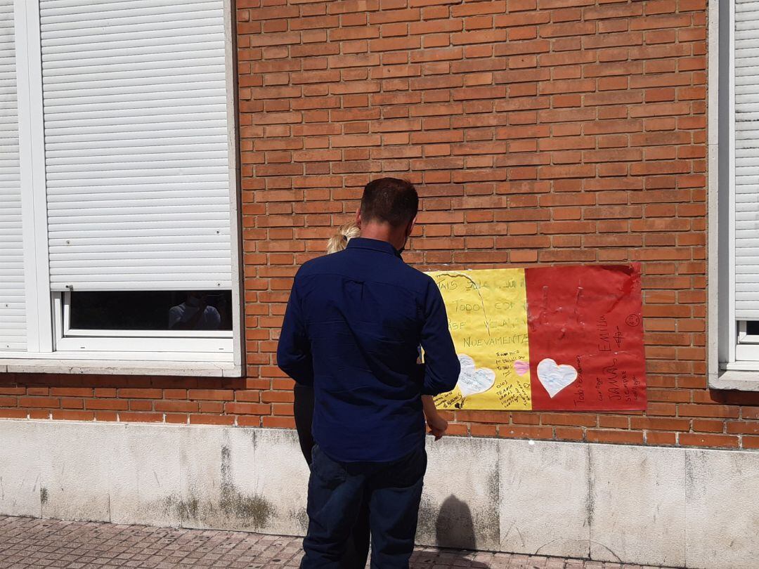 Familiares del joven agredido en Amorebieta ante el cartel de apoyo que se ha colocado en la fachada del hospital de Cruces, donde permanece ingresado 