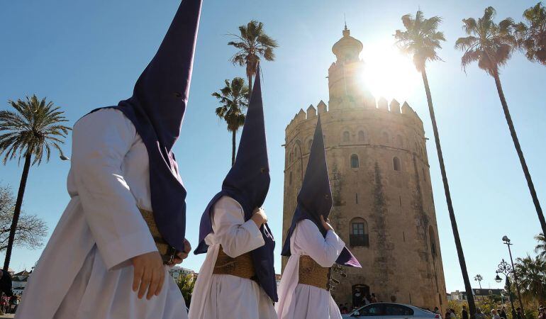 Nazarenos de Las Aguas pasando ante la Torre del Oro camino de su capilla en la tarde del Lunes Santo