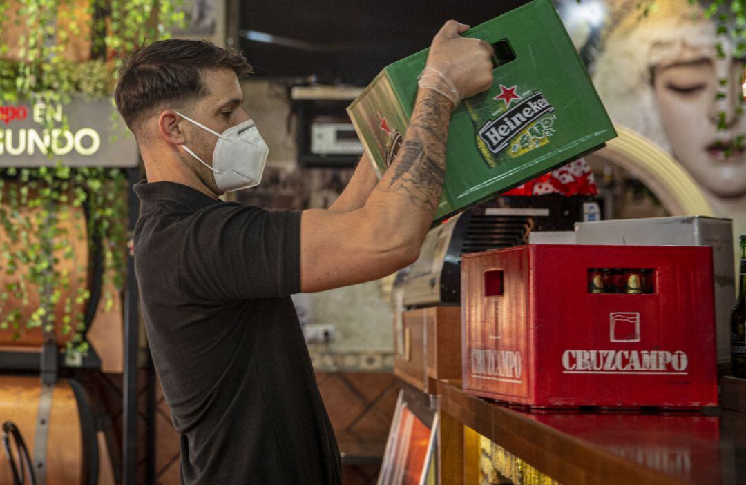 Un camarero coloca cajas de bebidas en el bar