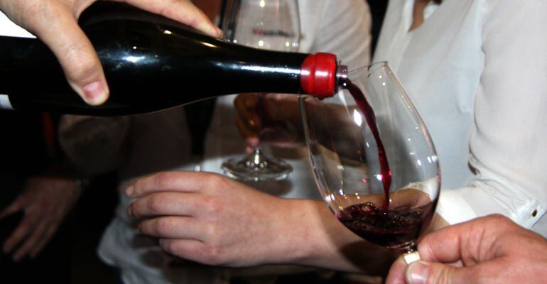 Pla detall d'una ampolla servint una copa de vi