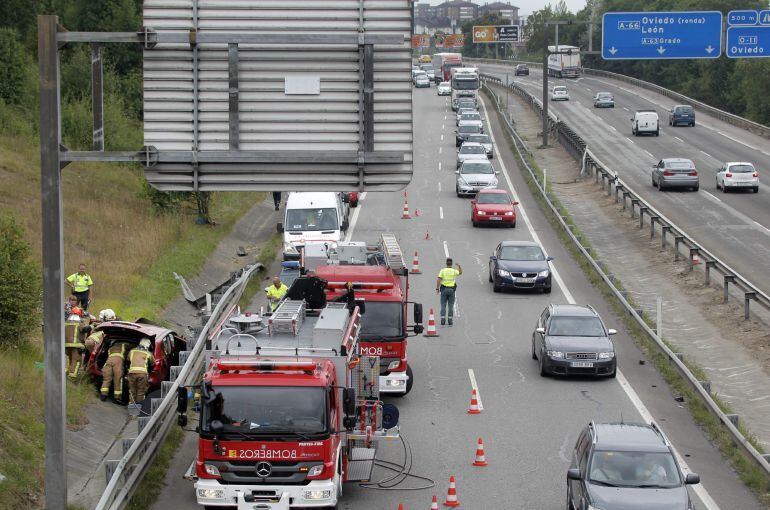 GRA292. OVIEDO, 15/07/2015.-Efectivos de Bomberos han excarcelado a uno de los dos ocupantes del coche (i) que se ha salido de la carretera en la A-66 a la altura de Oviedo en dirección Gijón, el accidente ha causado retenciones de varios kilómetros que l