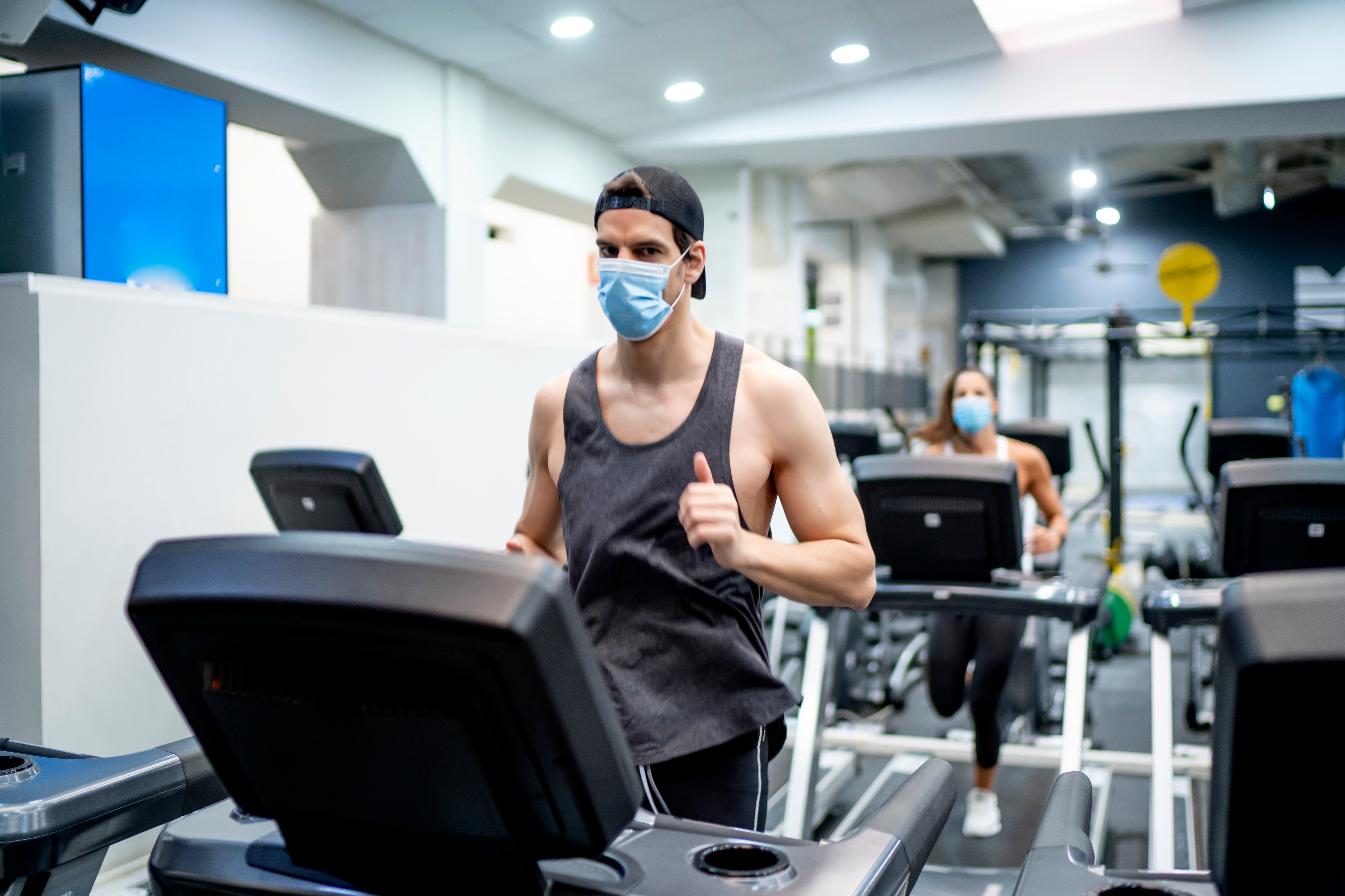 Una persona entrena en un gimnasio con la mascarilla