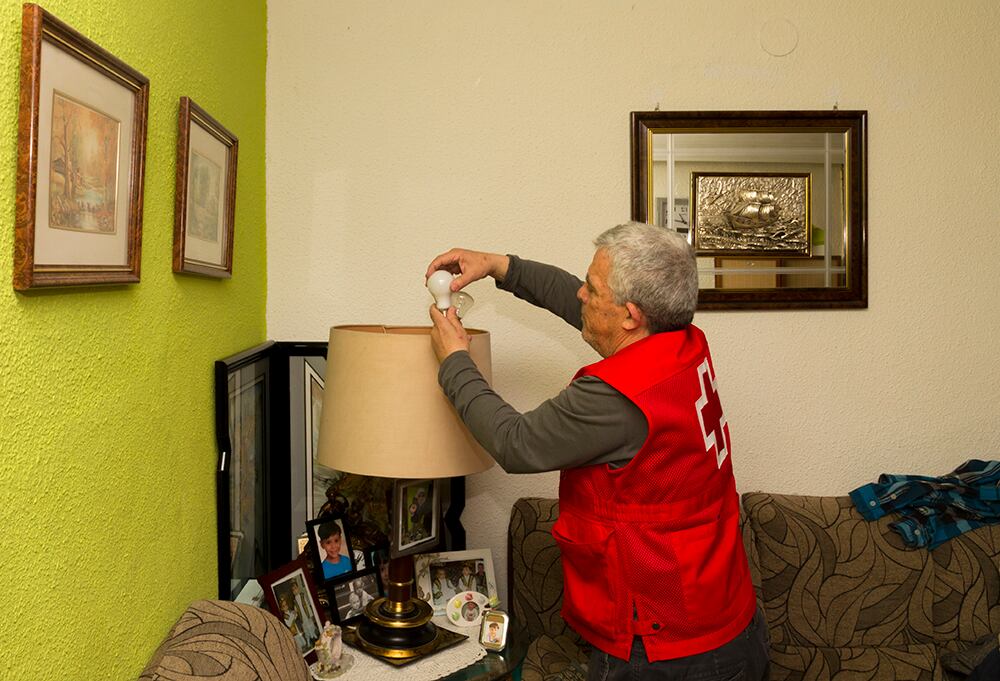 Un miembro de Cruz Roja cambia bombillas en un domicilio