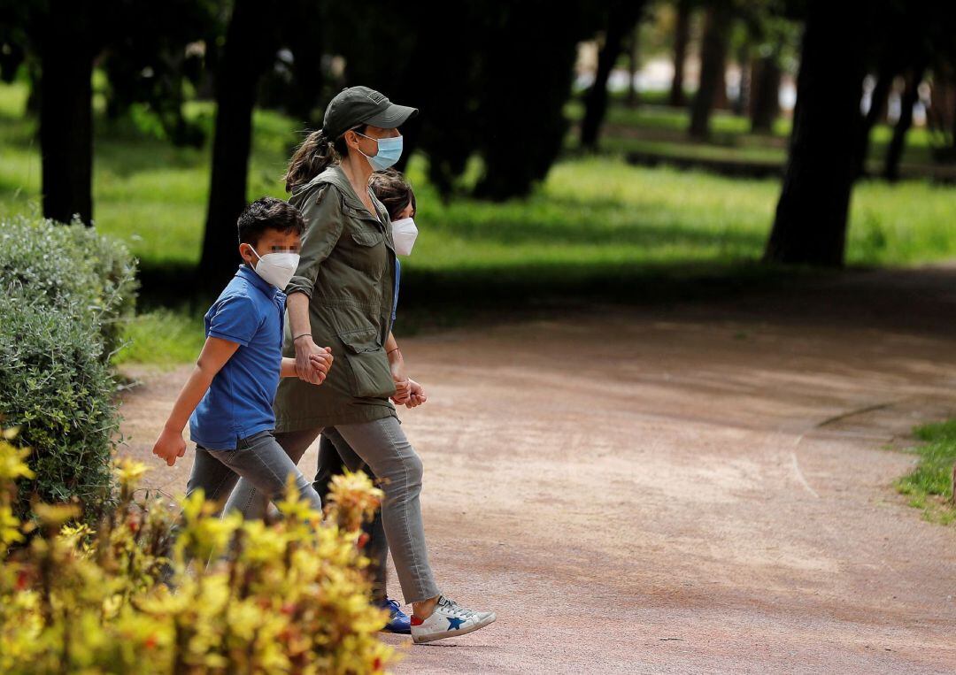 Una mujer pasea con dos niños por el jardín del rio Turia en el cuadragésimo cuarto día del estado de alarma.