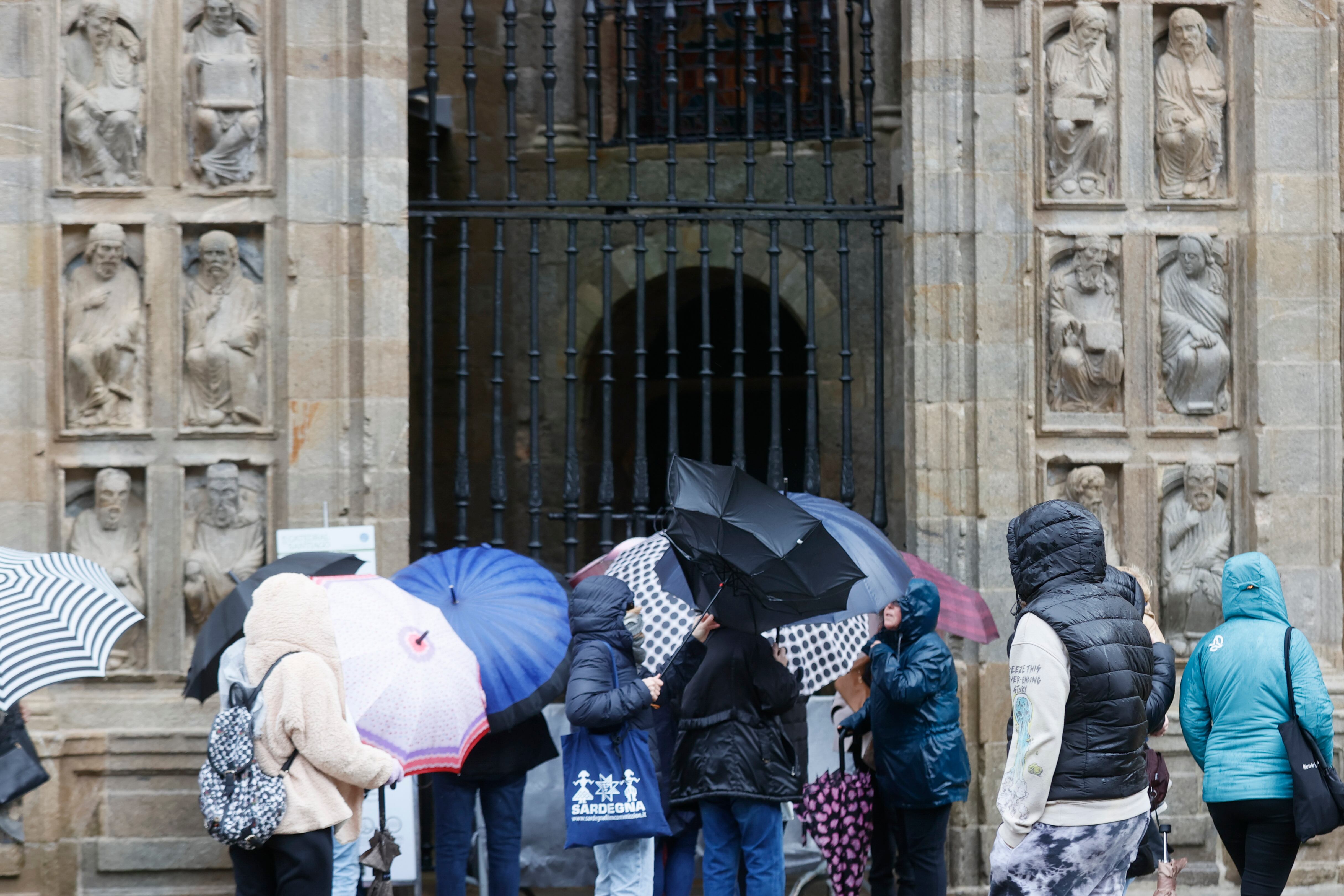 Un grupo de turistas aguardan bajo la lluvia para entrar por la Puerta Santa a la Catedral de Santiago de Compostela