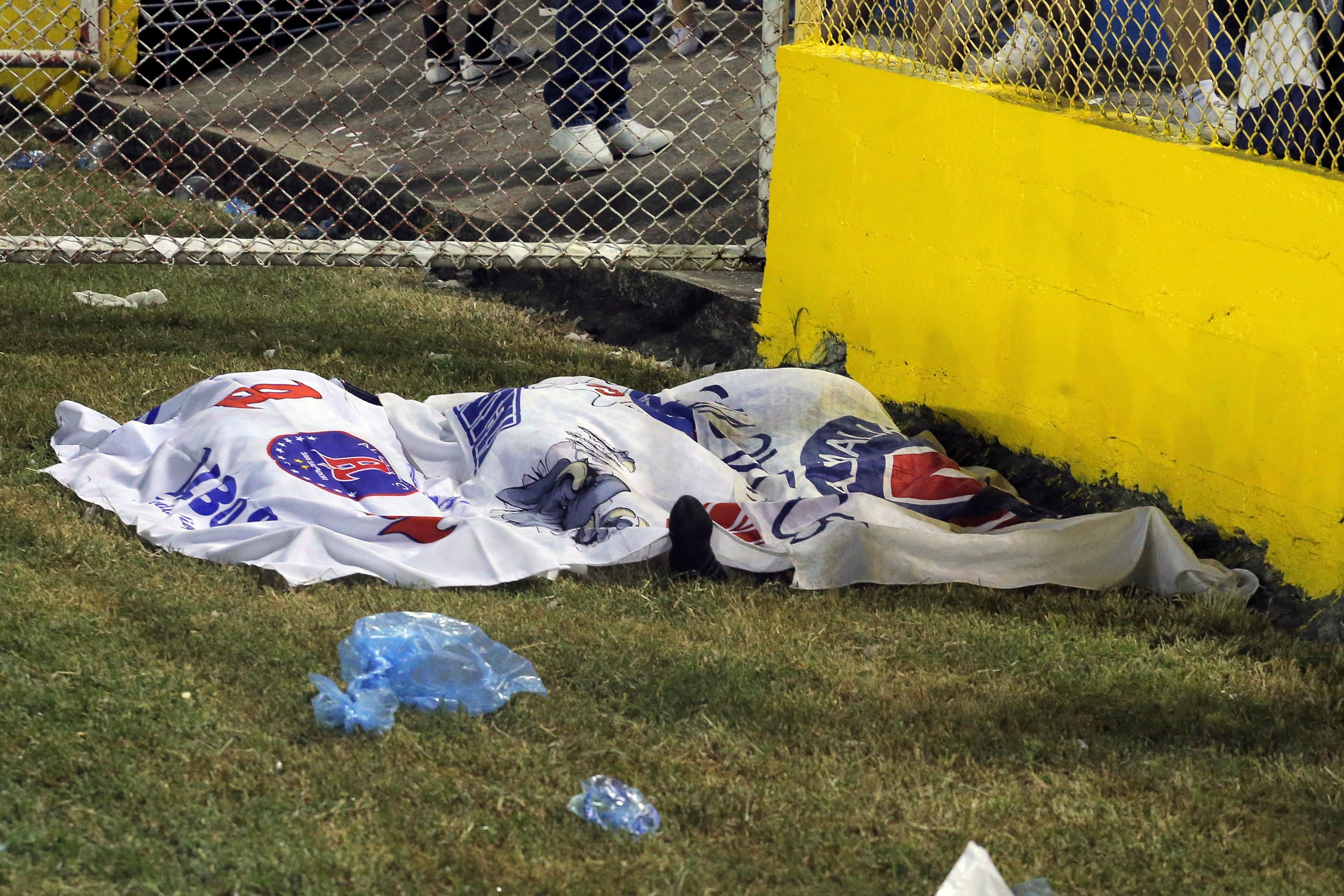 Una manta cubre varios cadáveres sobre el césped del Estadio Cuscatlán.