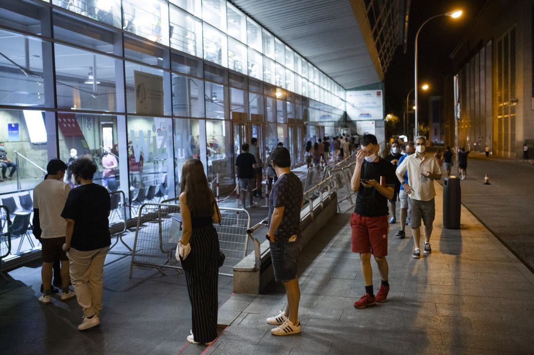 Fila de personas que esperan para recibir una dosis de la vacuna de Pfizer en el Wizink Center durante la primera noche en la que el recinto está abierto a la vacunación