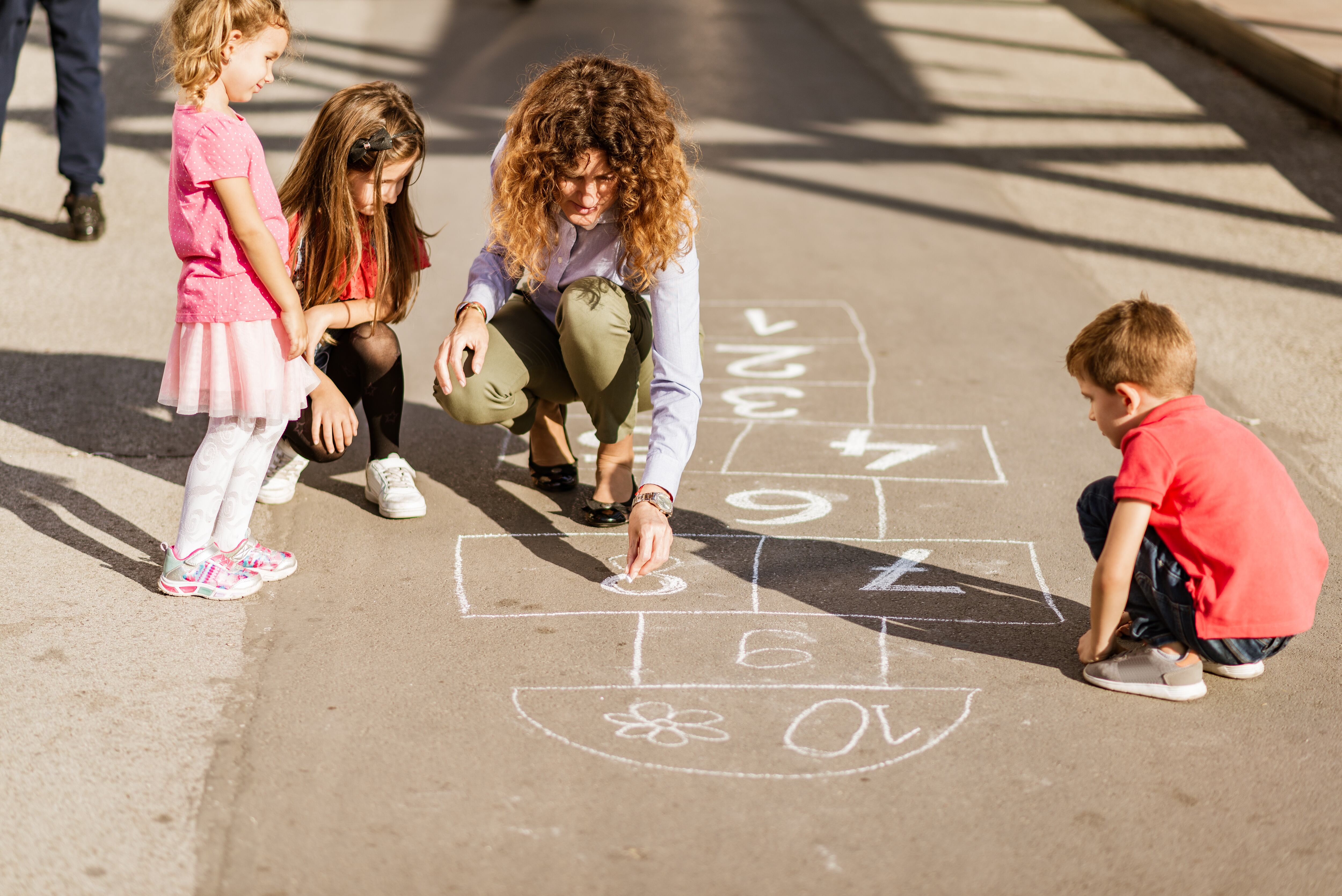 Monitora jugando con los niños en el patio de un colegio.