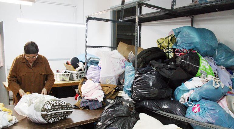 Una voluntària de Càritas repassa la roba que reben per mirar que estigui en bones condicions.